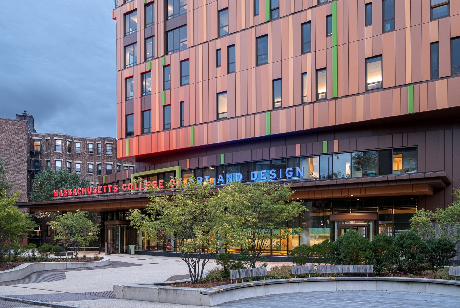 Architectural Photography of the Massachusetts College of Art and Design (MassArt) Tree House Student Residence in Boston Massachusetts designed by ADD Inc featuring a dramatic twilight image of the building lit against a dark cloudy sky