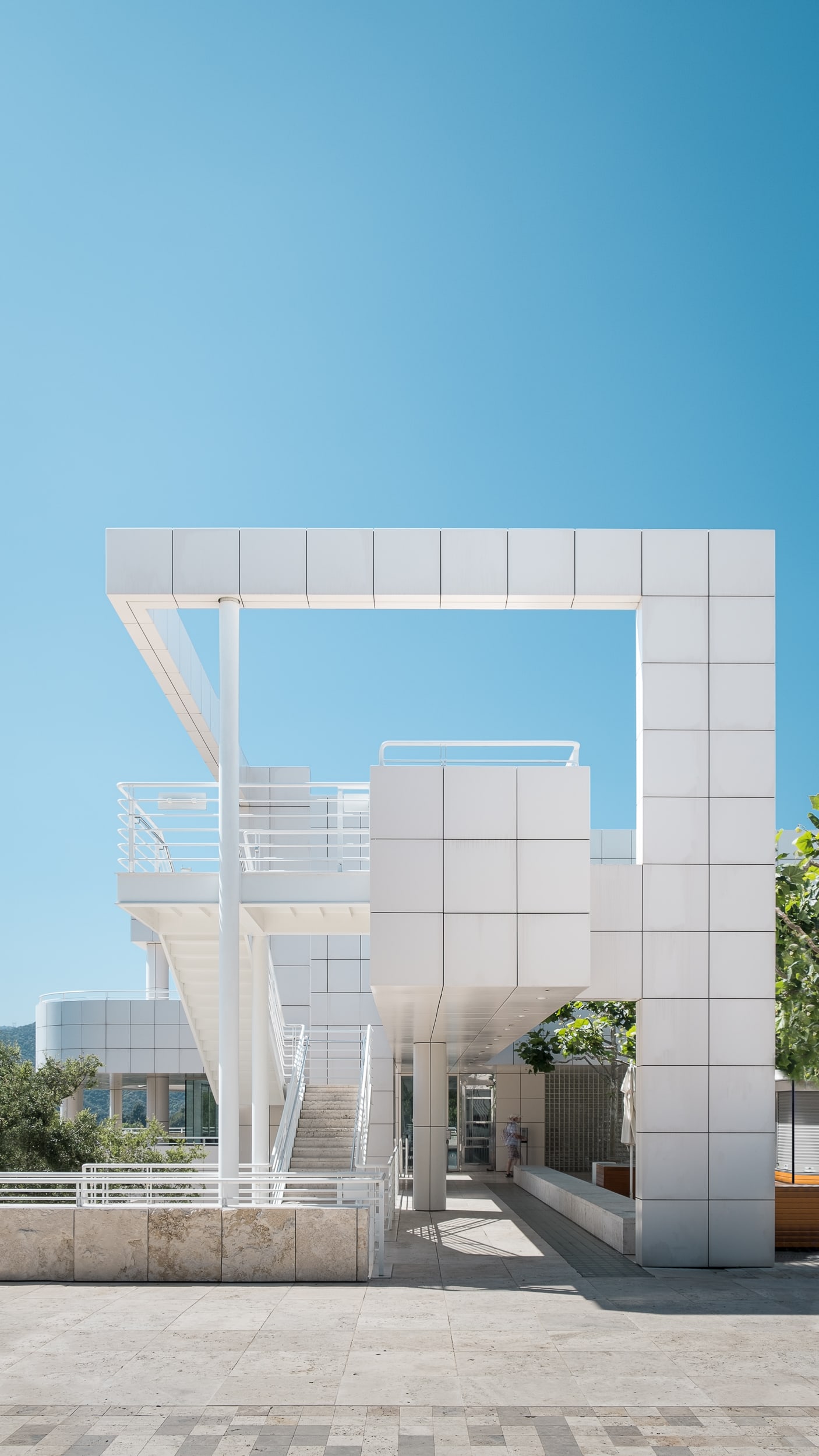 Architectural Photograph of the Getty Center in Los Angeles designed by Richard Meier and Partners featuring a one point perspective of the cafe building's unique shape from the entrance and characteristic white paneling