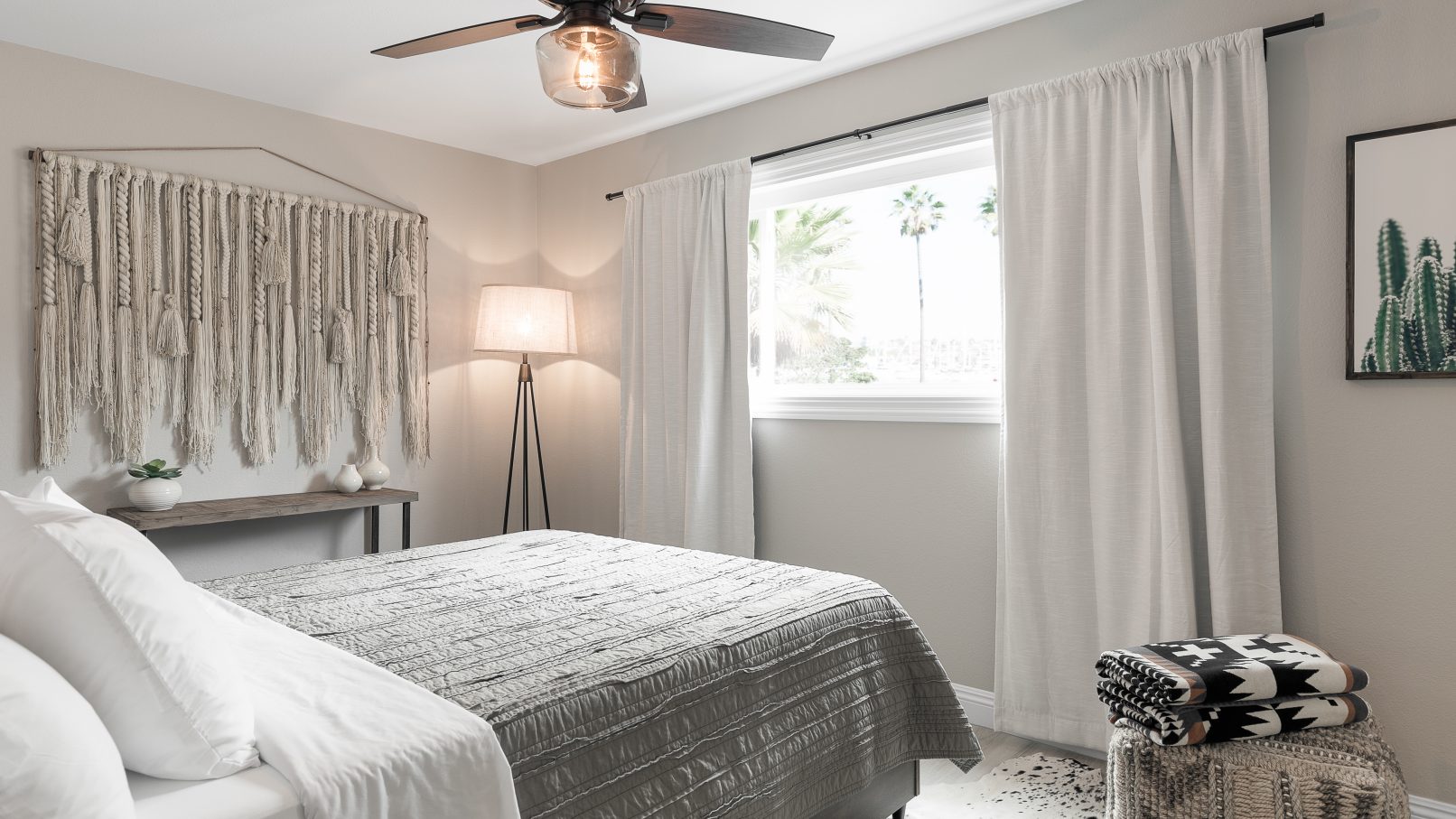 Orange County Interior Design Photography in Huntington Beach California featuring a bedroom in muted beige tones with macrame on the wall and delicate linens and lighting features throughout