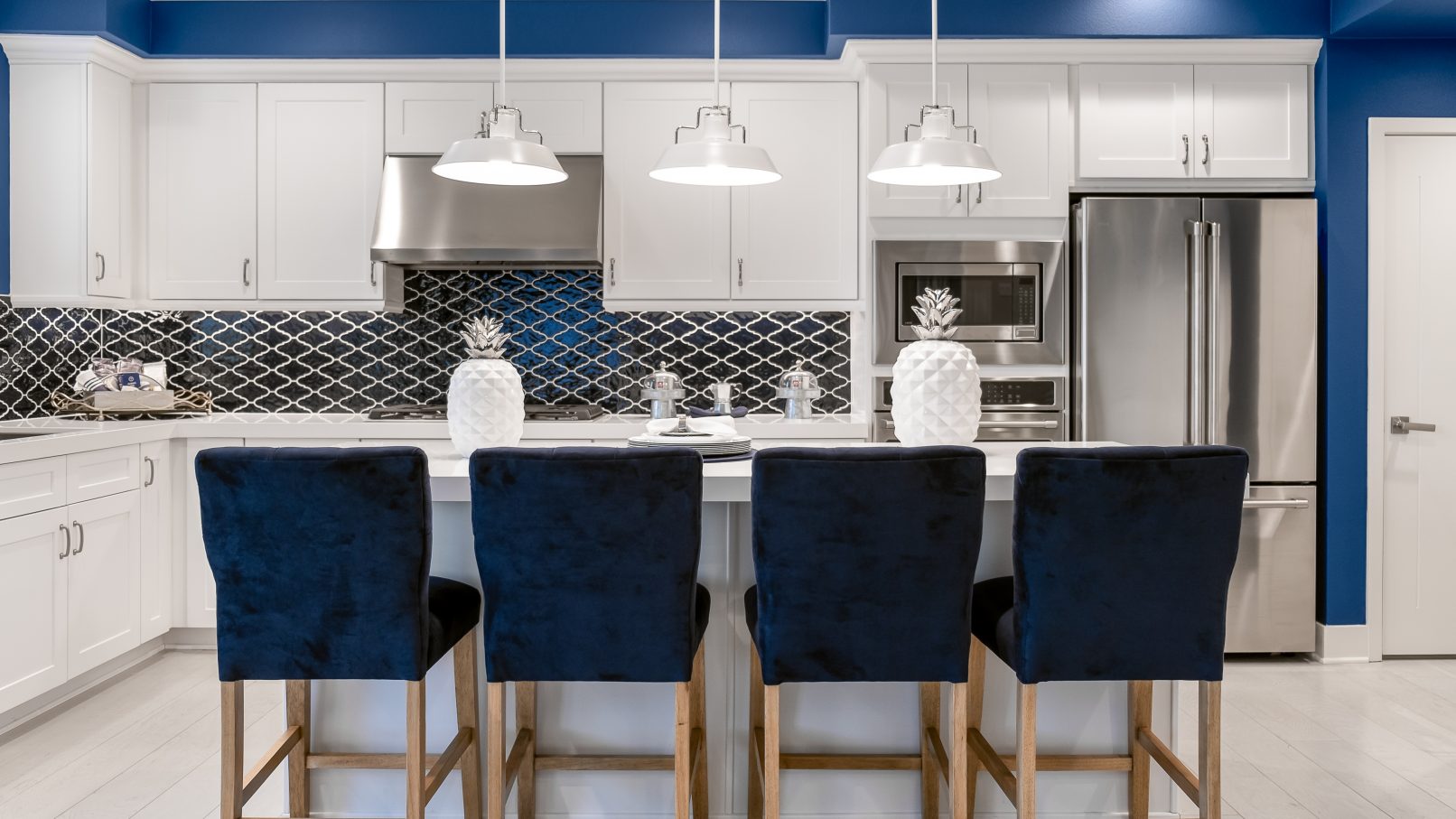 Orange County Interior Design Photography Irvine Blue Kitchen with Blue Barstools White Cabinets and Stainless Steel Appliances and Pendant Lamps with Pineapple Decor on Kitchen Island Counter
