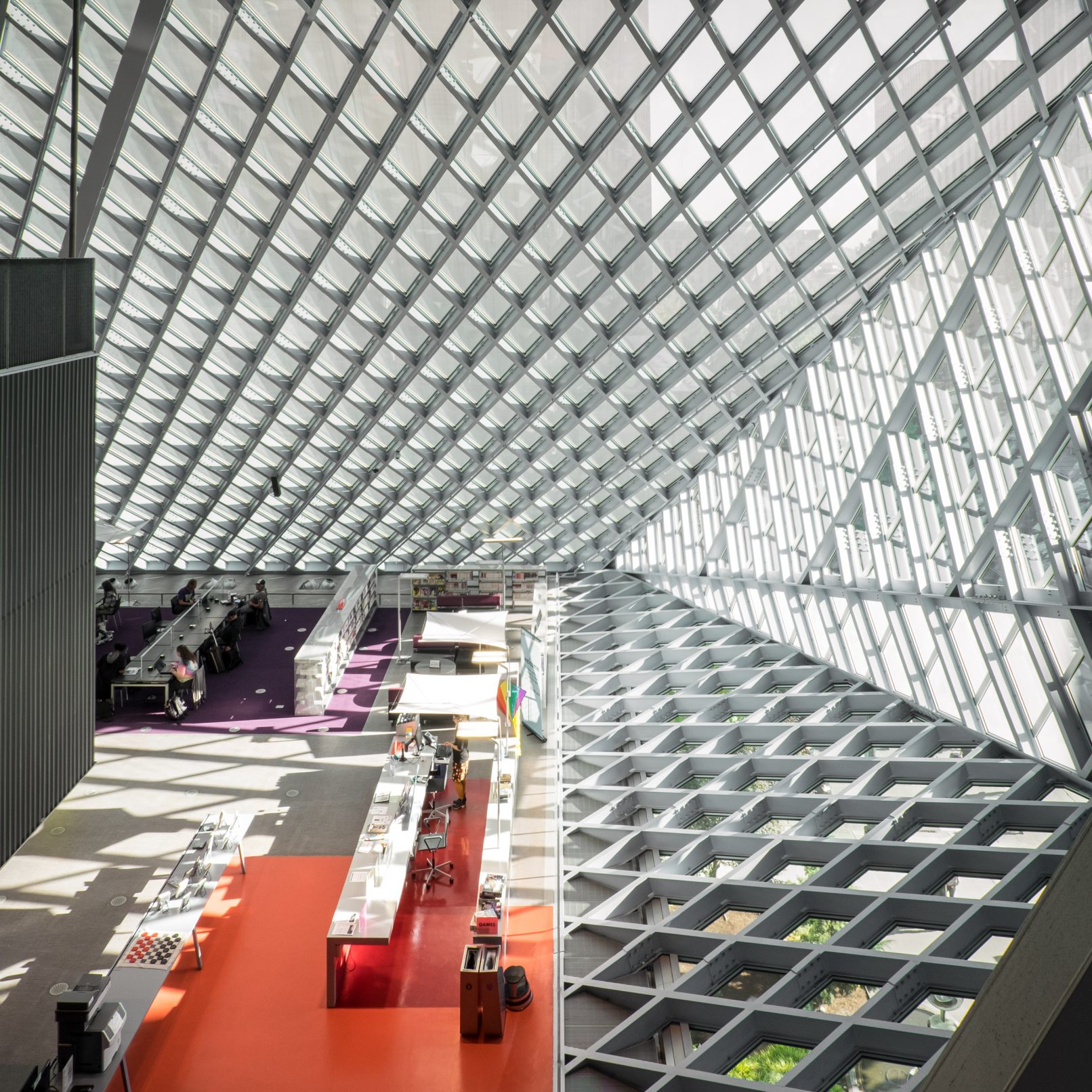 Architectural photography of the Seattle Central Library designed by OMA featuring a one point perspective of the interior looking down at the reference desk on the main floor